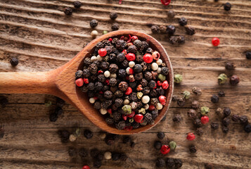wooden spoon with multicolored peppercorns on wooden desk