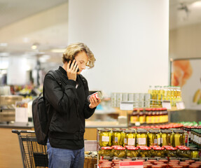 Young man shopping in supermarket, reading product information.