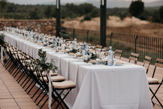 Outdoor wedding reception with white bunting flags and string lights and view on Spanish landscape