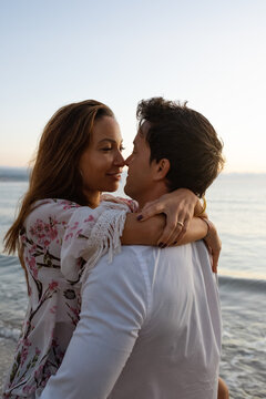 Young couple hugging on seashore at sundown