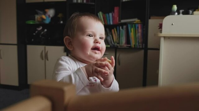 Caucasian small baby is eating something while watching TV