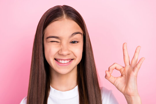 Photo of beautiful young pretty small girl show hand fingers okay sign isolated on pink color background
