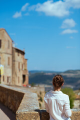 Seen from behind modern solo traveller woman in Tuscany, Italy