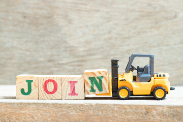 Toy forklift hold letter block n to complete word join on wood background