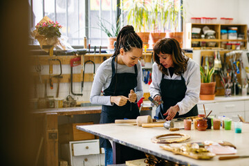 Craftswomen restoring woodwork in workshop 