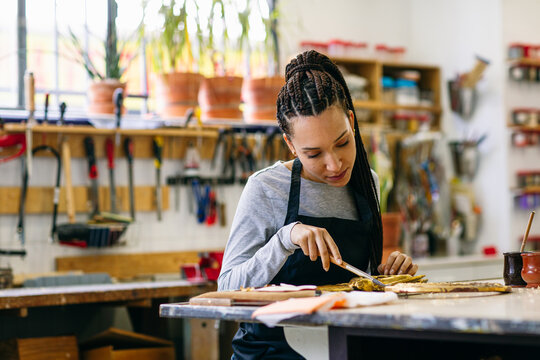 Focused artisan woman working in restoration workshop 