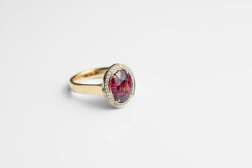 Beautiful expensive gold ring with rhodolite and diamonds on a white background