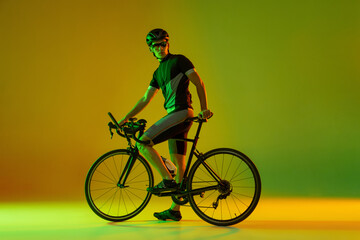 Fototapeta premium Cyclist riding a bicycle isolated against neon background