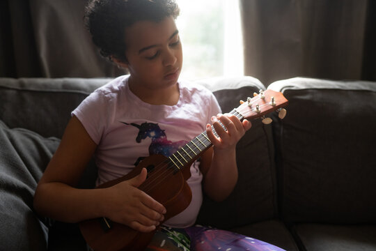 Young girl on couch playing ukulele