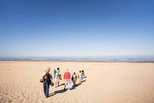 Multigenerational family walks across sandy beach