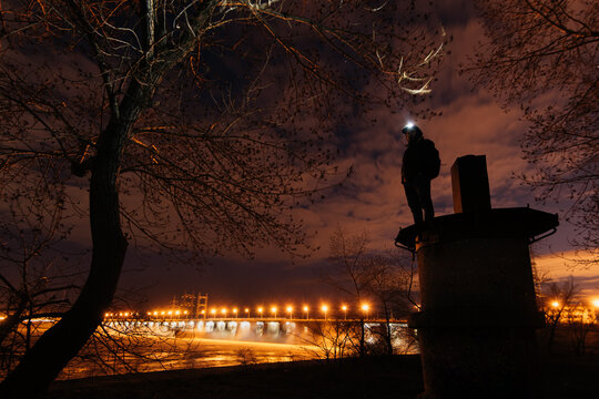 Man watching water discharge at night by a hydropower electric station 
