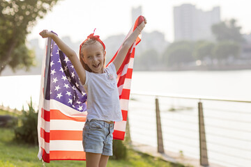 Patriotic holiday. Happy family, mother and daughter with American flag outdoors on sunset. USA...