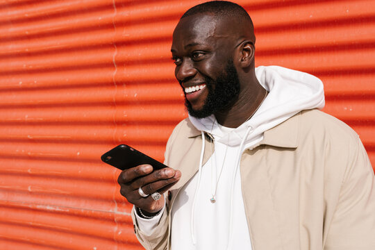 Black man sending voice messages by mobile on the street