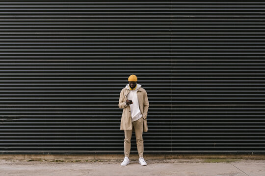 Man using mobile in front of a metal wall