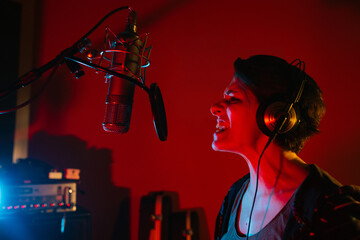 Vocalist singing into professional microphone in recording studio