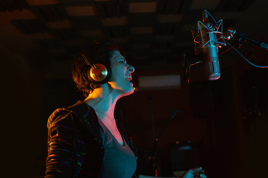 Vocalist singing into professional microphone in recording studio