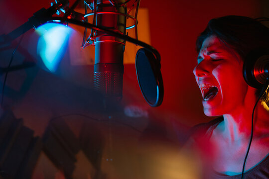 Vocalist singing into professional microphone in recording studio