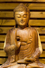 there is an illuminated wooden buddha meditating on a wooden background