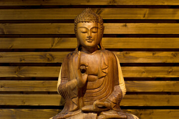 there is an illuminated wooden buddha meditating on a wooden background