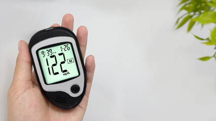 hold a diabetic glucose meter to check high blood sugar levels high blood sugar, white background