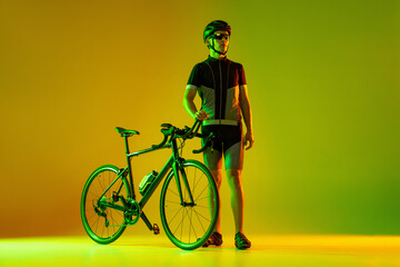 Fototapeta na wymiar Cyclist riding a bicycle isolated against neon background