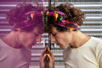 Portrait of a transgender woman with thoughtful gesture reflected on pink background