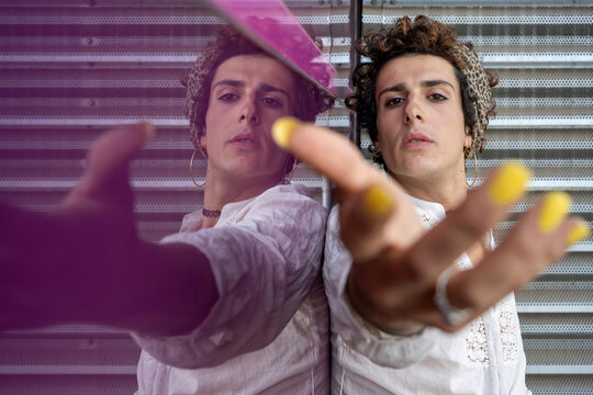 Portrait of a transgender woman reflected on pink wall 