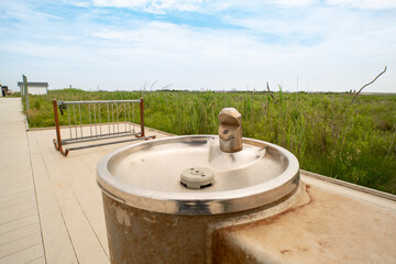 questionable rusted concrete and stainless steel public fresh drinking water fountain at Atlantic ocean beach front bike parking rack and pedestrian sidewalk