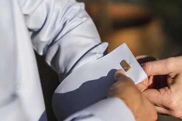 Closeup shot of a groom buttoning cufflinks and preparing for a wedding