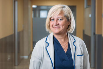 Happy real senior medic woman standing in hospital corridor