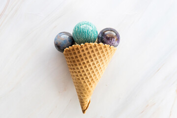Ice cream cone with round crystal stones on marble background as an spiritual or healing concept