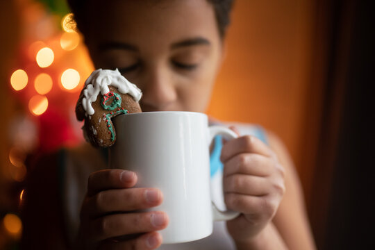 child drinks from mug with gingerbread house