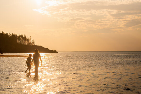 Mother and Son Walking Along Red Sand Beach on PEI at Sunset
