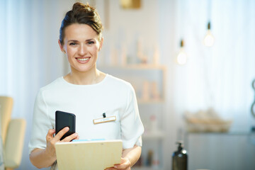 smiling woman worker with clipboard in modern beauty salon