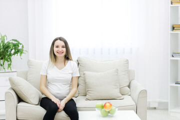 Fototapeta na wymiar Cropped photo of pregnant woman sitting on white sofa.