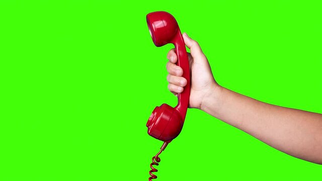 Hand holding the receiver of a retro red telephone