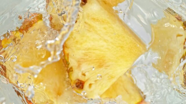 Super Slow Motion Shot of Pineapple Slices Falling Into Water Whirl at 1000 fps.