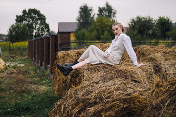 Naklejka na ściany i meble beautiful young woman in a light dress on a haystack. Agriculture.