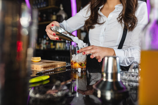 Anonymous stylish woman preparing alcoholic cocktail in modern bar
