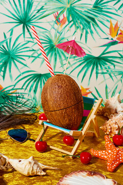 coconut ornamented with a paper umbrella on a small deck chair