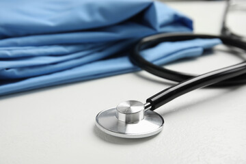 Stethoscope and medical uniform on white background, closeup