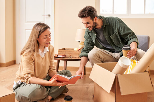 Happy couple reading notebook while unpacking box