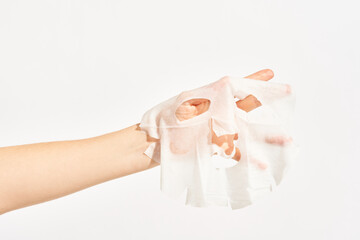 Woman with cosmetic sheet mask on hand