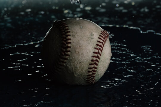 Dark Moody Baseball In Water With Shallow Depth Of Field And Selective Focus Close Up, Sports Rain Out Concept.