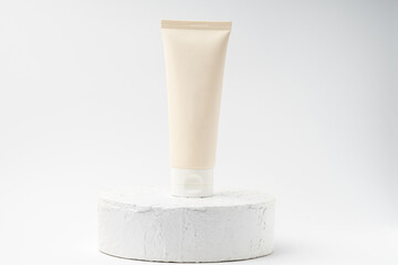 unbranded white tube of cosmetic product on white pedestal or podium on white background. skin care lotion or cream on a trendy display