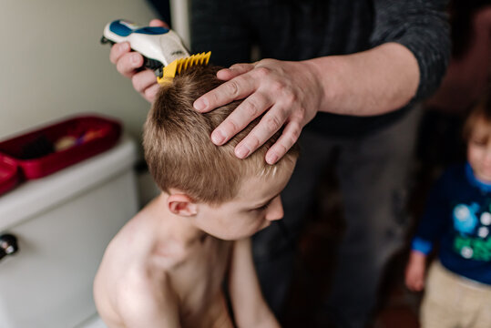 Close up image of a young boy having his hair cut at home