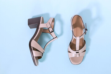 Classic beige women's sandals with medium heels on a blue background. The concept of sales and...