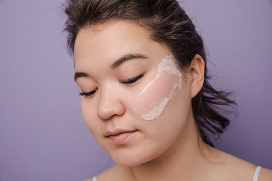 Beautiful east asian model with pink clay mask leftovers on her face 
