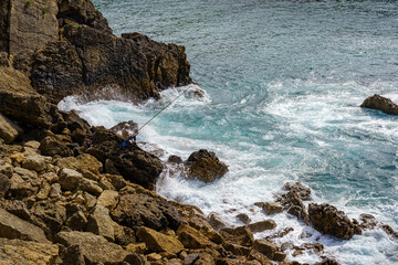 Man fished on the rock cliffs with strong waves of the sea. Santander.