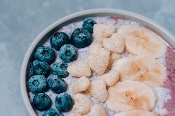 Healthy breakfast berry smoothie bowl topped with banana, granola, Blueberries and chia seeds with copy space